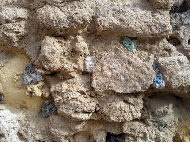 A wall in the city of Zwara, where holes have been filled with coloured plastic bags and then eroded by either wind or sun or eaten by goats. Photograph by Hadia Gana, November 2011. Courtesy and &copy; Hadia Gana. 