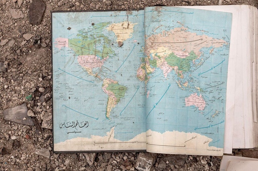 Carole Alfarah. An old world map inside a book found in the rubble in a destroyed neighborhood in Homs with Arabic writing &lsquo;The Global World. Political&rsquo;. Homs, Syria, 2014. 
